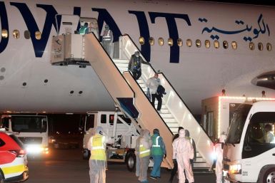Kuwaitis returning home from Frankfurt are met by health workers in decontamination suits late last month