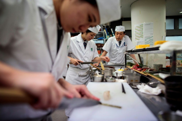 Fumimasa Murakami (R), a teacher at Tokyo Sushi Academy, watches his female students as they prepare sushi