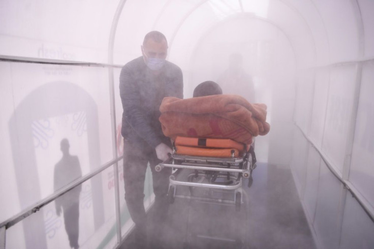 A health worker walks a patient through a disinfection chamber set tp  in front of a hospital in Mitrovica, Kosovo