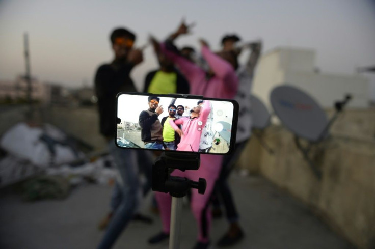 People pose while making a TikTok video on the terrace of their residence in India