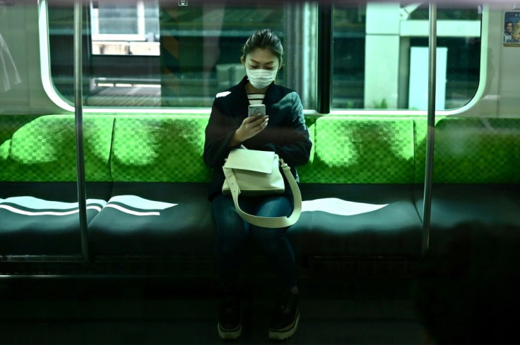 A woman uses her phone on the Yamanote Line train in Tokyo on the first day of the state of emergency