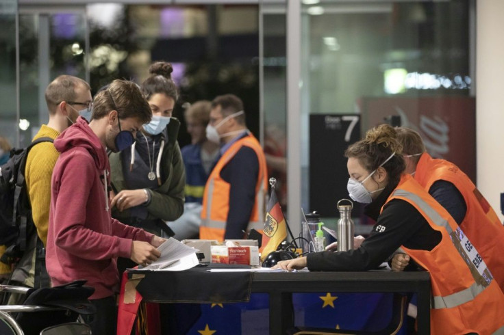 Embassy staff check  documents ofÂ German tourists as they prepare to check inÂ before boarding a special flight for Frankfurt at Christchurch Airport in New Zealand