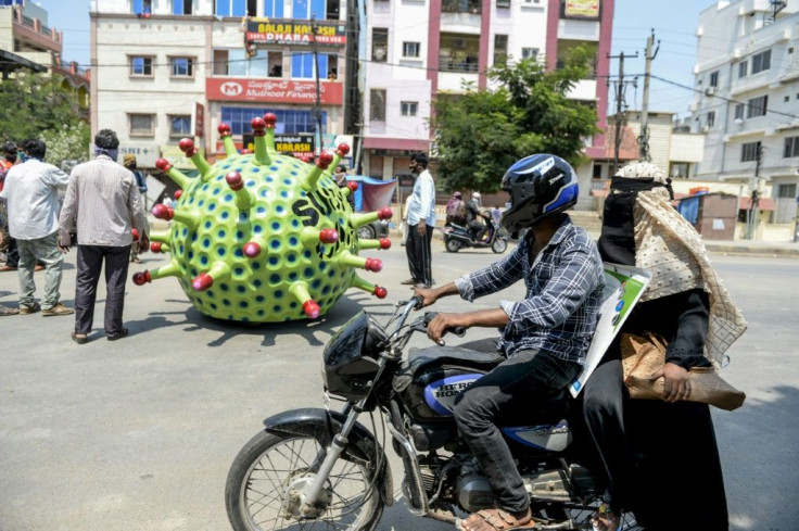 Drivers look on as Sudhakar Yadav (inside) drives his coronavirus-themed car through Hyderabad