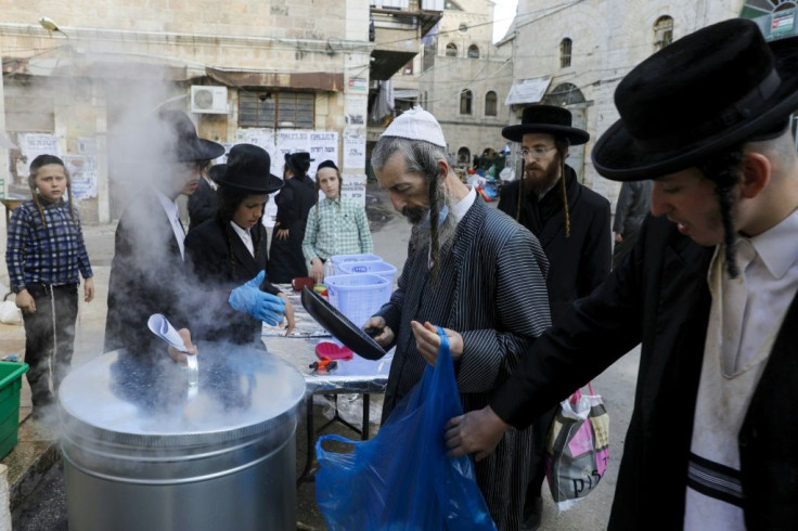 Ultra-Orthodox Jewish men dip their cooking utensils in boiling water to remove remains of leaven as they prepare for the Jewish holiday of Pesach (Passover) in Jerusalem's Mea Shearim neighbourhood