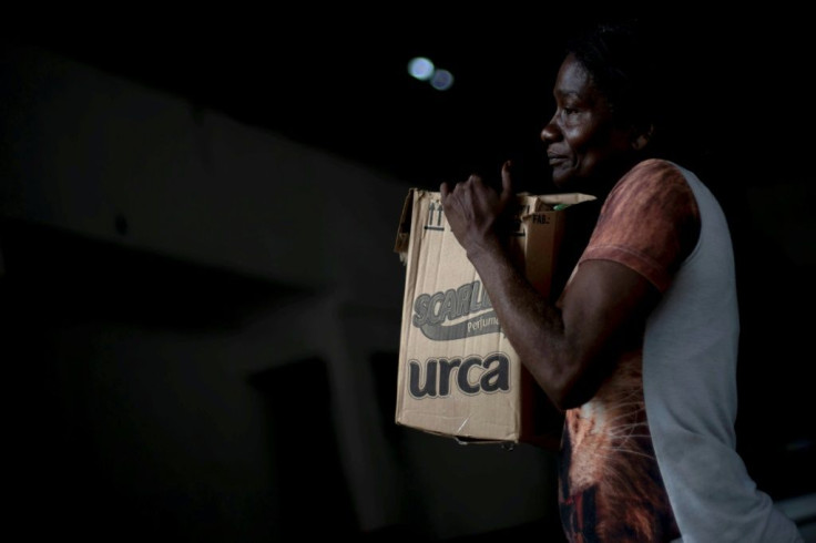A woman in Rio de Janeiro's City of God favela carries a box with donations of basic food supplies distributed by an NGO to people suffering economic hardship during the novel coronavirus in Brazil