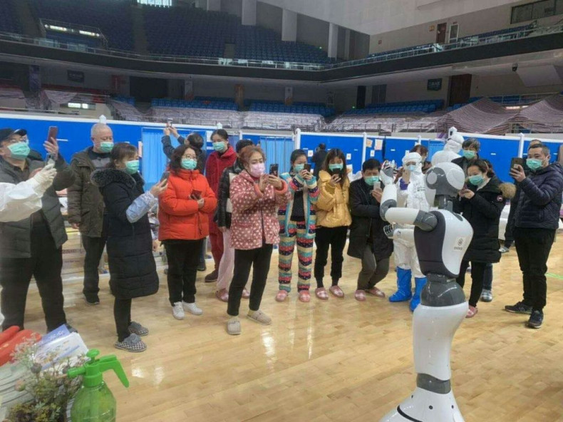 A handhout picture provided by CloudMinds shows Wuhan smart field hospital staff looking at an XR1 robot being deployed for coronavirus patient care