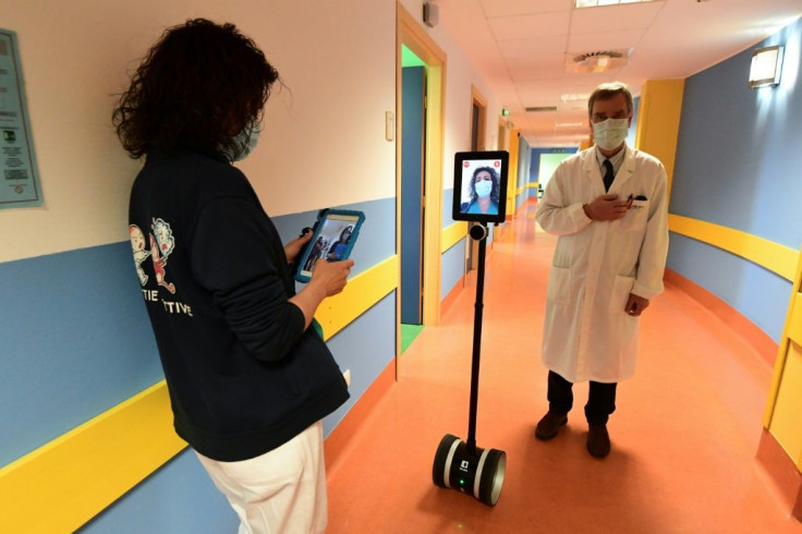 A nurse (L) manipulates a robot called Ivo used to help patients infected by the novel coronavirus at the Circolo di Varese hospital in Italy amid the the spread of the pandemic