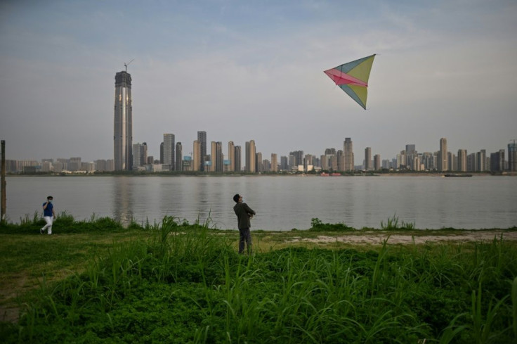 A man wearing a facemask flies a kite along the Yangtze River in Wuhan
