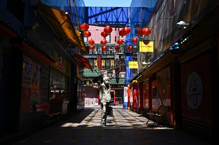 A man wearing a face mask stands in lane in the Chinatown area of Yokohama