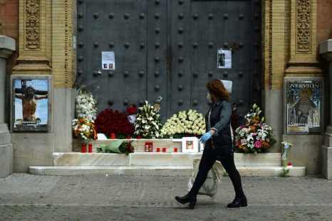 A woman walks past a church in Seville, adorned with flowers and candles left by the faithful after Easter processions were cancelled