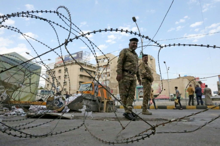 Iraqi policemen stand behind barbered wire during anti-government demonstrations in Baghdad's Tahrir Square on March 1, 2020