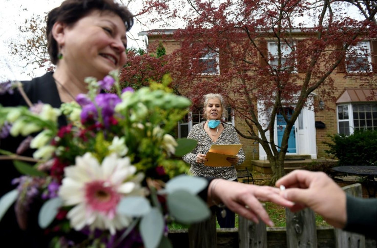 A newly married couple exchanges wedding rings in front of the home of a Virginia state marriage officiant who performs the ceremony while maintaining social distance due to the Coronavirus outbreak on April 1, 2020 in Arlington, Virginia.