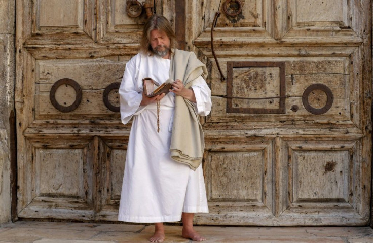 A worshipper prays in front of the closed door of the Holy Sepulchre Church in Jerusalem's Old City amid movement restrictions due to the coronavirus pandemic