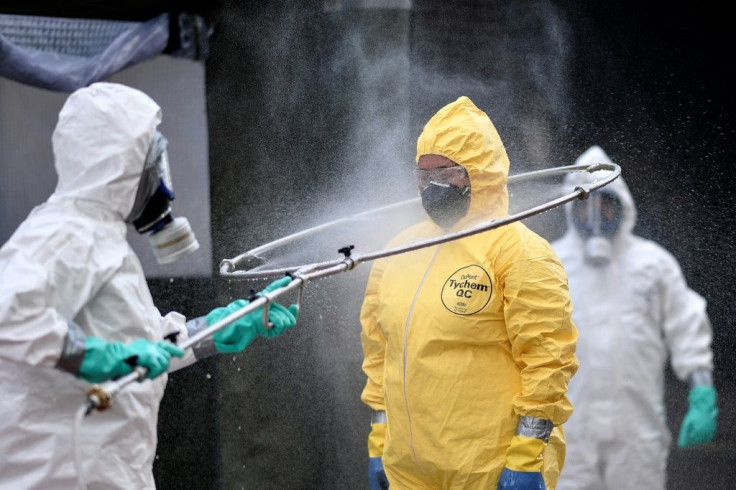 Brazil's military, firefighters and Civil Defense members disinfect each other after cleaning a bus station in Belo Horizonte, Brazil