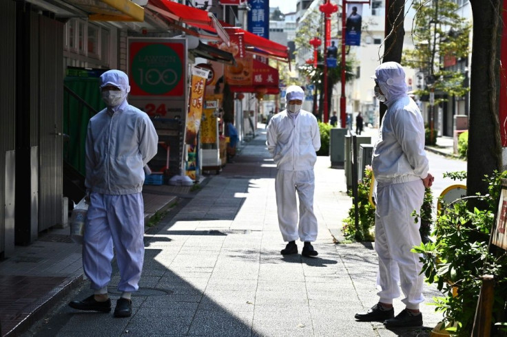 Employees of a restaurant wearing masks stand outside their eatery before it opens in the Chinatown area in Yokohama, Japan