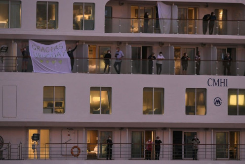 Passengers of the coronavirus-stricken Australian liner Greg Mortimer display a sheet reading "Thank You Uruguay" as the cruise ship arrives at Montevideo's port on April 10, 2020