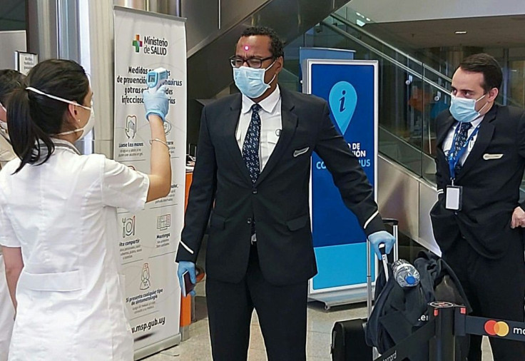 This handout photo released by Uruguay's Foreign Ministry shows crew members of the charter flight to Australia undergoing temperature checks at Carrasco international airport on April 10, 2020