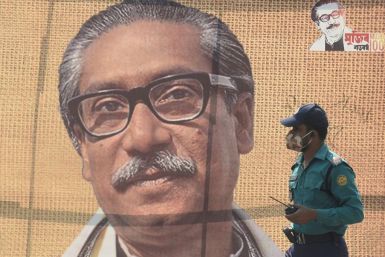 In this file photo taken on March 09, 2020 a policeman wearing a facemask amid fears of the spread of COVID-19 novel coronavirus, walks past a banner with a picture of Bangladeshâs founder Sheikh Mujibur Rahman in Dhaka