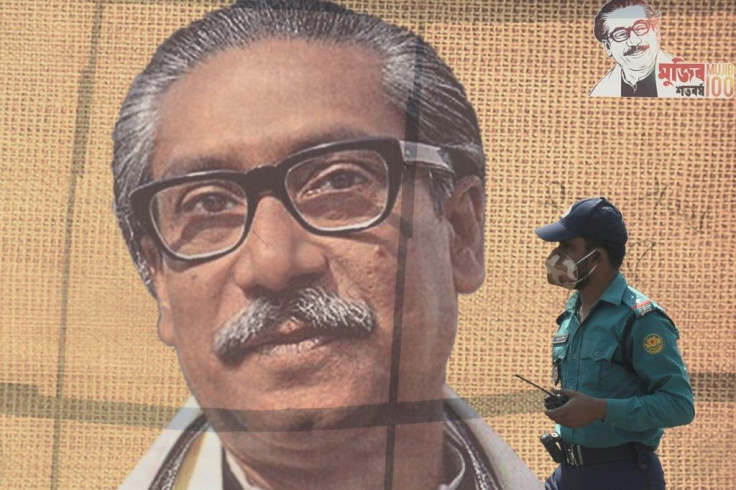 In this file photo taken on March 09, 2020 a policeman wearing a facemask amid fears of the spread of COVID-19 novel coronavirus, walks past a banner with a picture of Bangladeshâs founder Sheikh Mujibur Rahman in Dhaka
