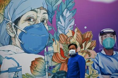 A man wearing a facemask walks in front of a mural at Leishenshan Hospital in Wuhan, China
