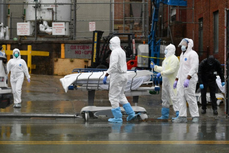 Medical personnel move a deceased patient to a refrigerated truck serving as a makeshift morgues at Brooklyn Hospital Center on April 9, 2020