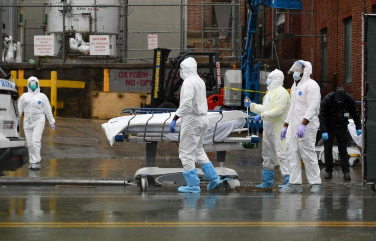 Medical personnel move a deceased patient to a refrigerated truck serving as a makeshift morgues at Brooklyn Hospital Center on April 9, 2020