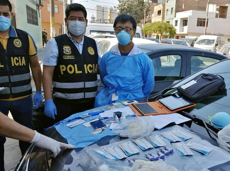 A Peruvian police photo showing Chinese citizen Zhang Tianxing (R) after his arrest for the unauthorized use of stolen COVID-19 tests in a street in Lima, on April 12, 2020