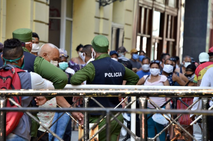 Cuban police control a line of people trying to buy food on Easter Sunday at a market in Havana amid the COVID-19 pandemic