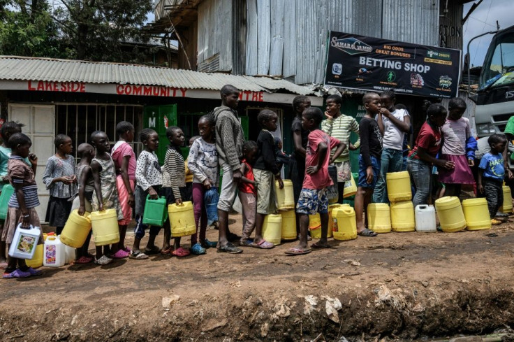 Children wait in line for water, distributed for free in the Nairobi slum of Kibera last week. Health experts say close queueing breaks the rule of social distancing to prevent virus infection