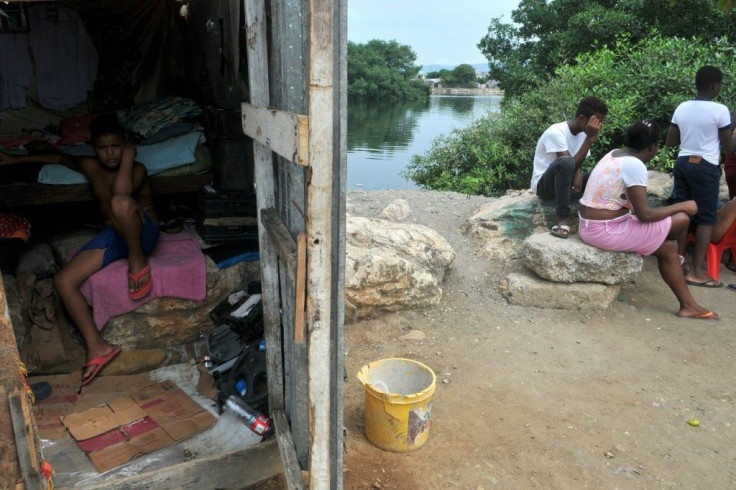 A child remains inside his home as his relatives sit out the COVID-19 epidemic in Guayaquil, Ecuador's Nigeria neighborhood