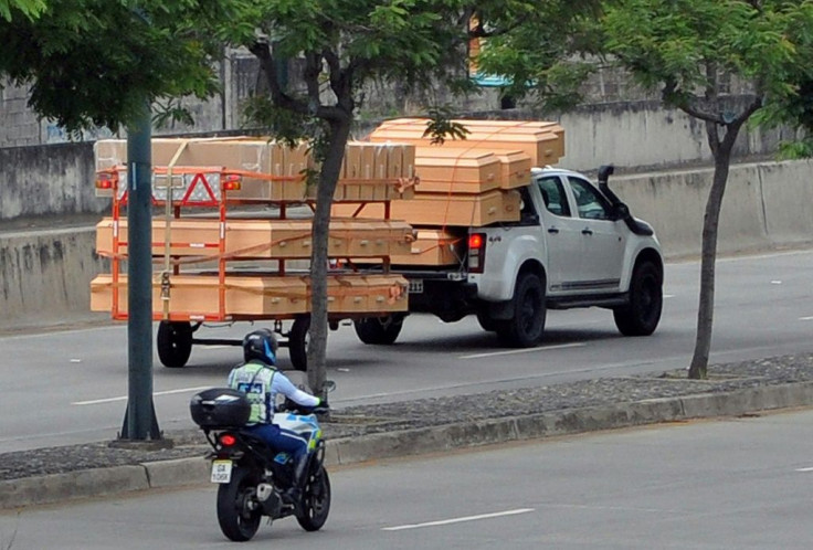 Coffins are seen stacked high on a pick-up truck and trailer as it passes a hospital in Guayaquil, Ecuador
