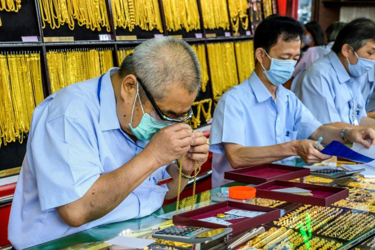 An gold shop employee checks a necklace offered for sale at a shop in Bangkok's Chinatown