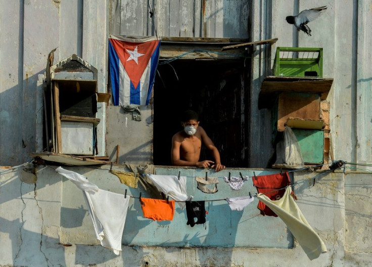 A man in a facemask stands on his balcony in Havana, Cuba