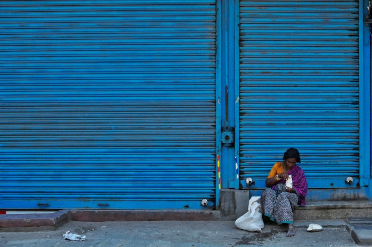 A homeless woman in the Indian city of Bangalore opens a food parcel distributed by a charity during the nationwide lockdown