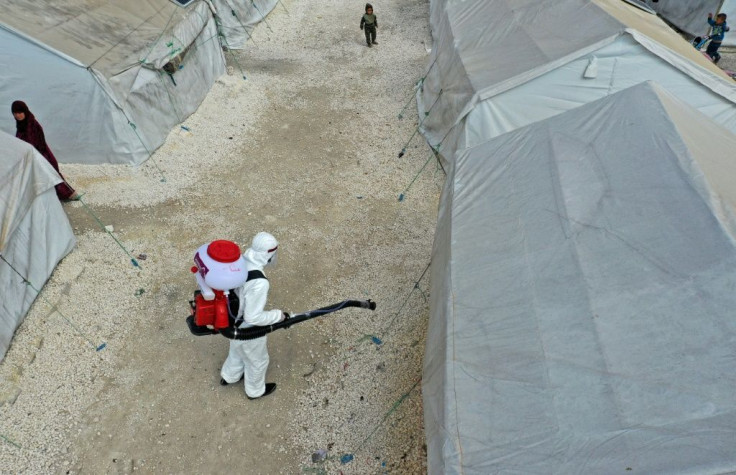 A sanitation worker disinfects a camp for displaced Syrians in the northwestern city of Idlib