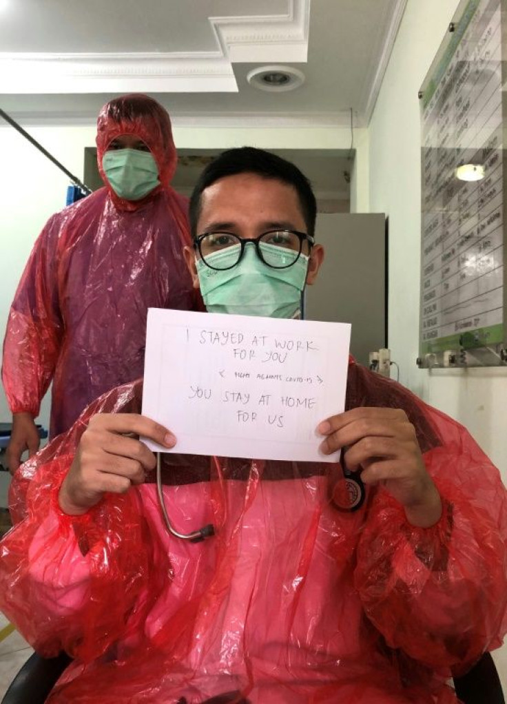 Doctor Muhammad Farras Hadyan, wearing a raincoat because of a shortage of proper protection gear, poses for a selfie during a break from treating patients with coronavirus, in Jakarta