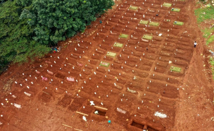 Grave diggers in hazmat suits prepare burial sites for coronavirus victims at a cemetery in Jakarta
