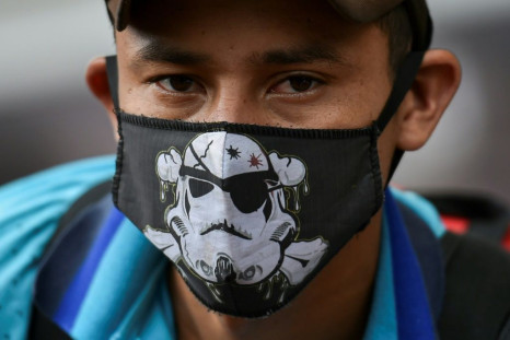 A Venezuelan migrant wears a face mask as he waits to board a bus to voluntarily return to his country because of the novel coronavirus in Cali, Colombia, on April 14