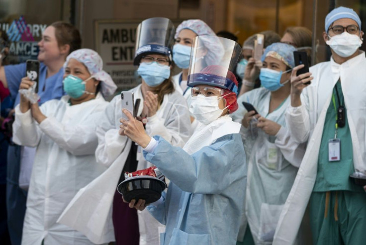 Health workers react to people applauding in front of Mount Sinai Hospital in Queens, New York to show gratitude to medical staff and essential workers on the front lines of the coronavirus pandemic