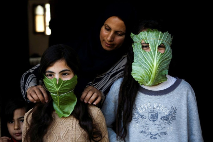 A Palestinian mother entertains her children with makeshift masks made of cabbage in Beit Lahia in the northern Gaza Strip on April 16, 2020