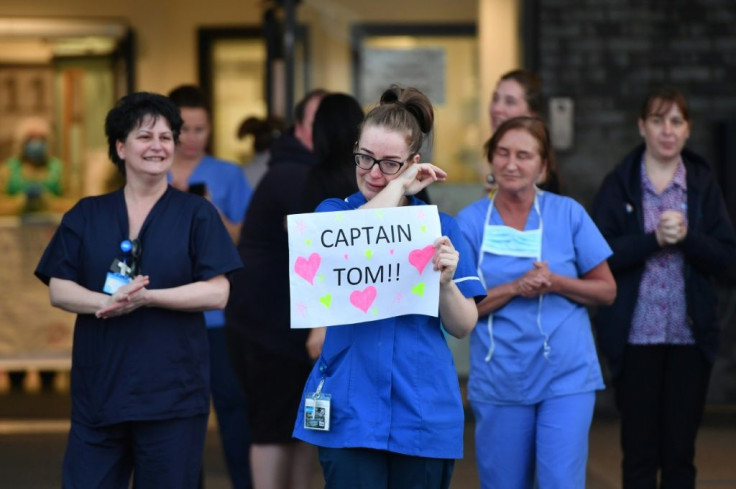 An NHS staff member wipes her eyes as she holds a sign to thank British veteran Captain Tom Moore, who raised over 13 million pounds for the NHS, as they take part in a national "clap for carers" in Liverpool, north-west England