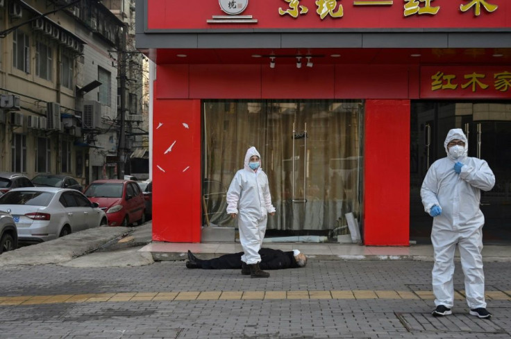 Health officials in Wuhan check on a man who collapsed in January. The Chinese city where the coronavirus first emerged raised its death toll by 50 percent on Friday, to a total of 3,869