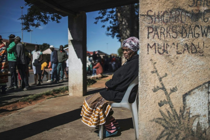 Informal traders and waste-pickers queue for food at a Soweto parking lot