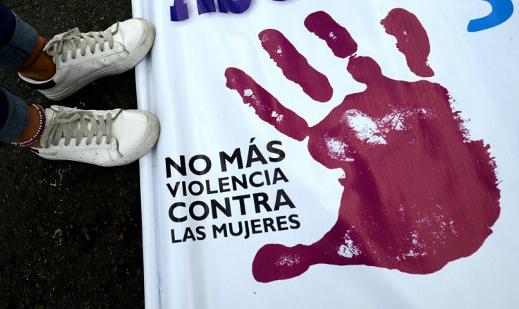A woman stands next to a banner reading "No More Violence Against Women" at a march in Lima, Peru