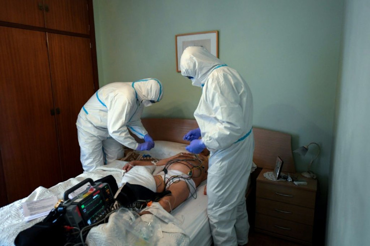 Health care workers in Madrid wearing protective suits examine a man who has fallen ill at home -- Spain is one of the countries worst hit by the coronavirus crisis