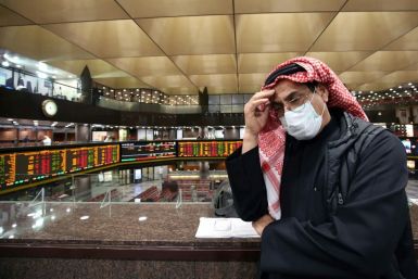 A trader wearing a face mask to protect against the coronavirus follows the market at Kuwait's stock exchange