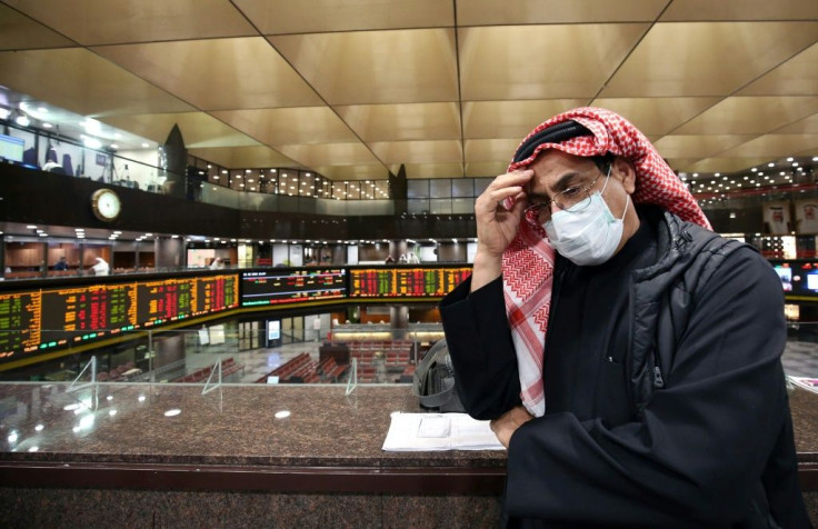 A trader wearing a face mask to protect against the coronavirus follows the market at Kuwait's stock exchange