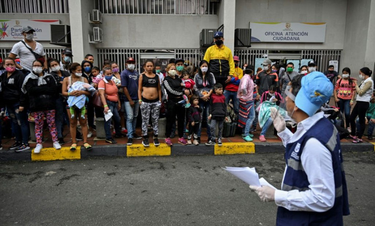 Venezuelan migrants listen to instructions from a city official in Cali, Colombia before boarding a bus for the border of Venezuela