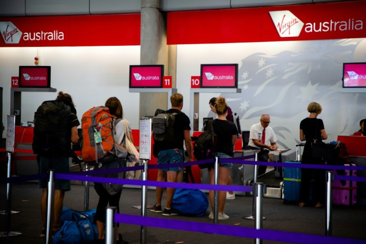 Passengers check-in at the Virgin Australia counter at Brisbane airport on April 21, 2020, after the carrier collapsed but said it would still keep operating flights