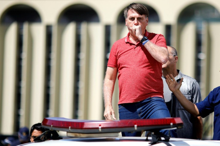 President Jair Bolsonaro coughs as he speaks to his supporters in Brasilia on April 19